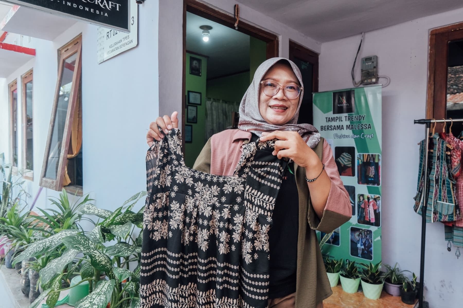 Foto Ibu Madu memamerkan produk Malessa Fashion berupa daster di depan toko.