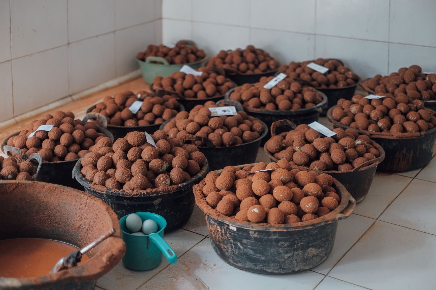 Foto beberapa ember berisi telur dibalut dengan adonan yang sedang diproses di dapur produksi.