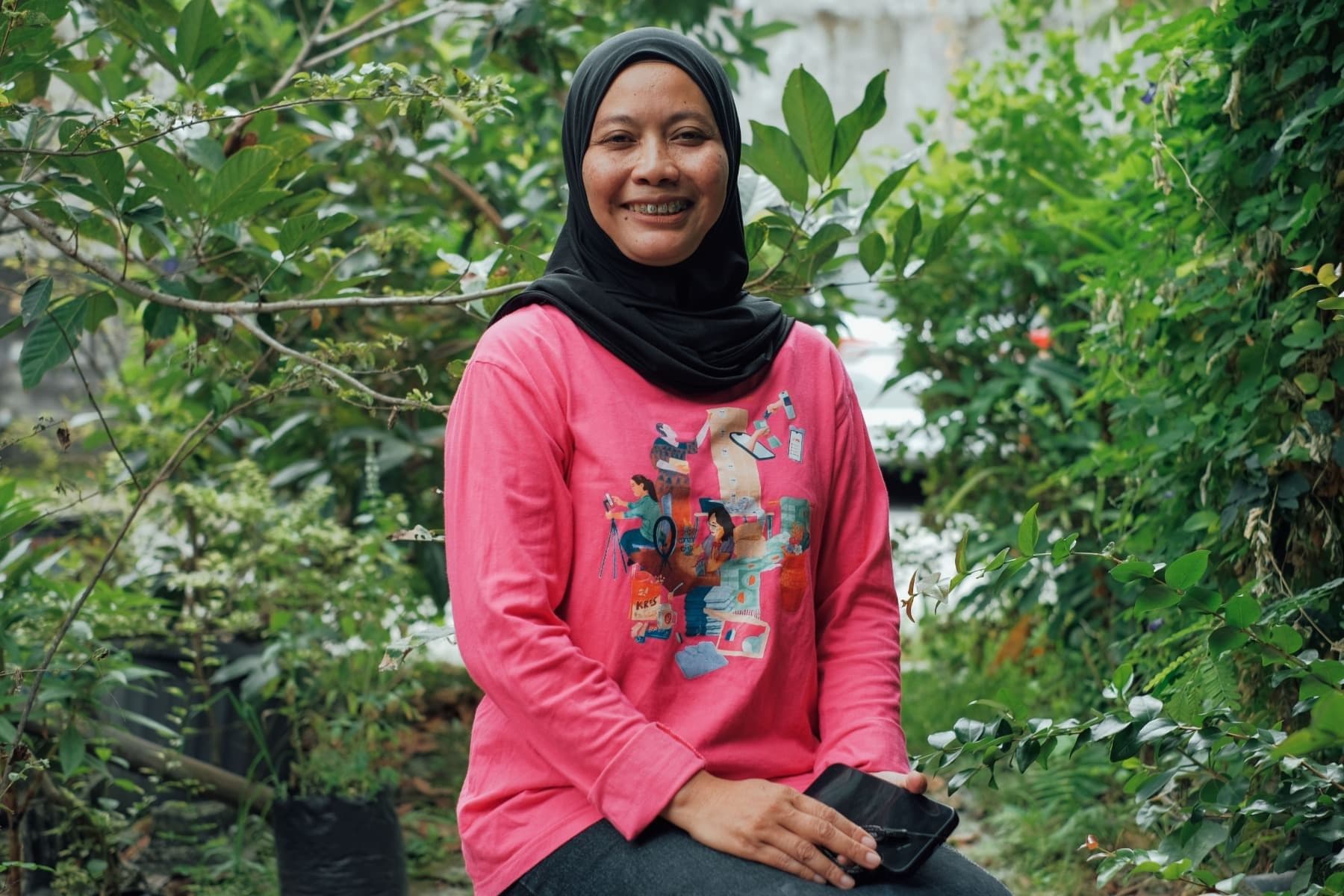 Foto Ibu Ida sedang duduk sembari tersenyum menghadap kamera.